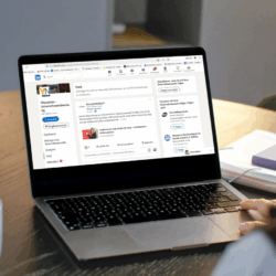 Eine Frau schaut auf einen Laptop. Auf dem Bildschirm ist LinkedIn geöffnet.